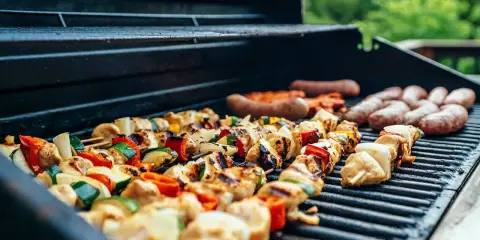 Brochettes de poulet et légumes, saucisses en cuisson barbecue gaz. L'été arrive, les grillades sont prêtes !