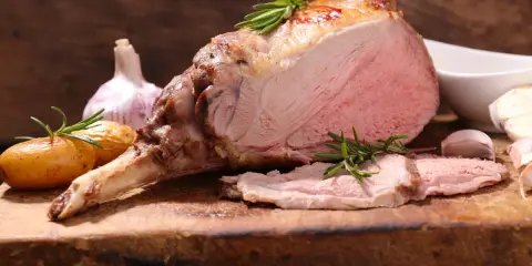 Un gigot d'agneau rôti, tendre et juteux, avec des pommes de terre et de l'ail. Ce gigot qui pleure de délice est prêt à être dégusté.