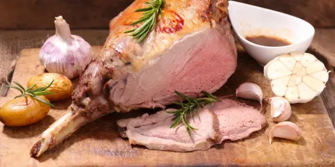 Gigot d'agneau rôti, tendre et juteux, servi avec des pommes de terre nouvelles, de l'ail et une sauce savoureuse. Un accompagnement parfait pour un repas festif.