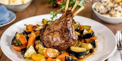 Un gigot d'agneau rôti, prêt pour un accompagnement gigot d'agneau pour Noël, servi avec des légumes de saison grillés.