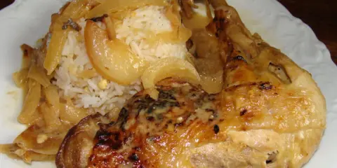 Un plat de poulet yassa savoureux avec du riz blanc et des oignons caramélisés.