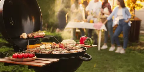 Un barbecue ouvert crépite, cuisant viandes et légumes sous un soleil doré. Des amis discutent joyeusement en arrière-plan, profitant d'un moment convivial.