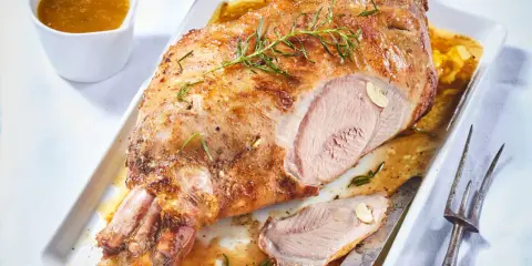 Gigot d'agneau pour 6 personnes, rôti à la perfection, servi avec sa sauce et garni de romarin.