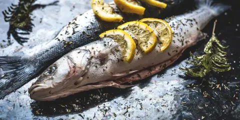 Deux poissons entiers, assaisonnés d'herbes et garnis de rondelles de citron, prêts pour un quel poisson barbecue.