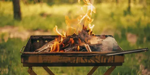 Un brasero crache des flammes vives, signe qu'il est temps de choisir quel bois pour barbecue afin de savourer un repas en plein air.