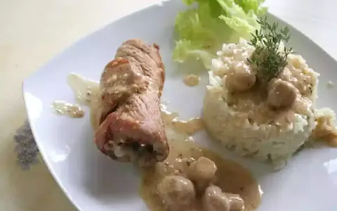 Délicieuse roulade de porc en sauce crémeuse, accompagnée d'une timbale de riz et d'une feuille de laitue.