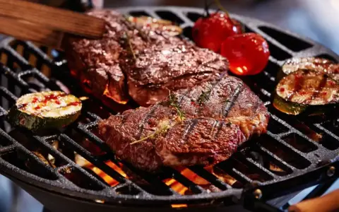 Un délicieux barbecue hivernal avec des steaks juteux, des tomates cerises et des courgettes grillées sur un feu vif.