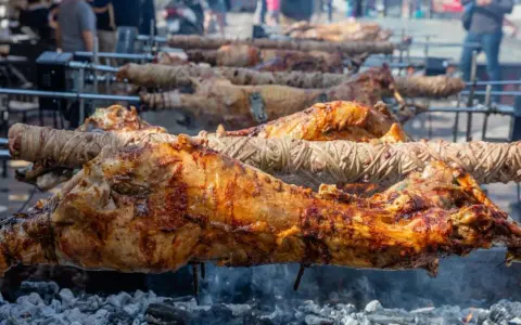 Plusieurs agneaux à la broche rôtissent lentement sur des feux de bois. La peau dorée et croustillante promet un délice savoureux.