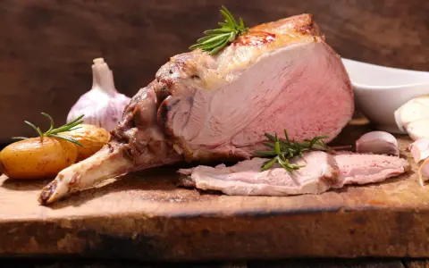 Un gigot d'agneau rôti, tendre et juteux, avec des pommes de terre et de l'ail. Ce gigot qui pleure de délice est prêt à être dégusté.