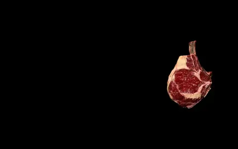 Un morceau de t bone boeuf, avec son os apparent, est présenté sur fond noir. Son emplacement est sur la droite de l'image.