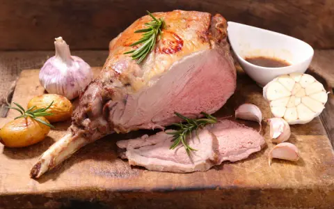 Gigot d'agneau rôti, tendre et juteux, servi avec des pommes de terre nouvelles, de l'ail et une sauce savoureuse. Un accompagnement parfait pour un repas festif.