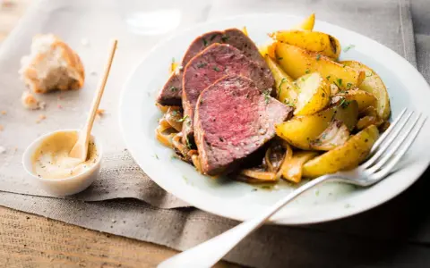 Tranches de roti de boeuf tendre, accompagnées de pommes de terre rôties et d'une sauce moutarde crémeuse.