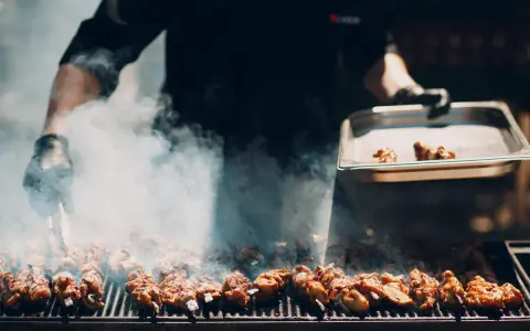 Un chef prépare un délicieux barbecue italien, des brochettes de viande fumantes sur le grill.