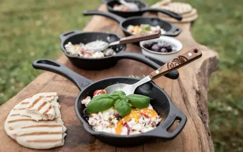 Petits woks de fromage frais, tomates et herbes, servis sur une planche en bois avec du pain grillé. Parfait pour un bbq.