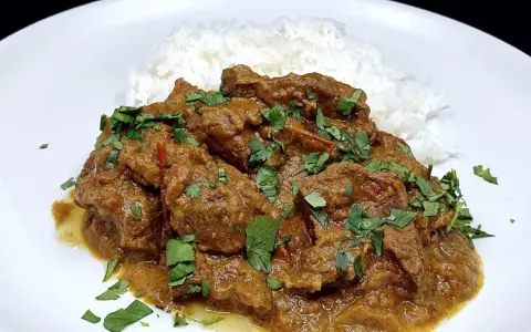 Un savoureux curry d'agneau, mijoté et garni de coriandre fraîche, servi avec du riz blanc.