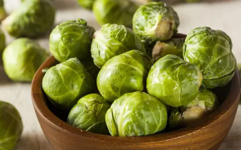 Un bol en bois rempli de choux de Bruxelles frais et verts. Ces petits légumes verts sont prêts à être cuisinés.