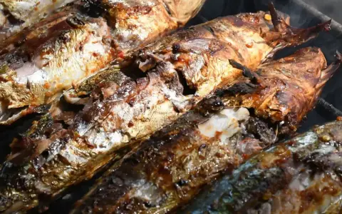 Plusieurs poissons entiers, dorés et appétissants, cuisent sur un barbecue au charbon. Quel poisson au barbecue charbon, une merveille !