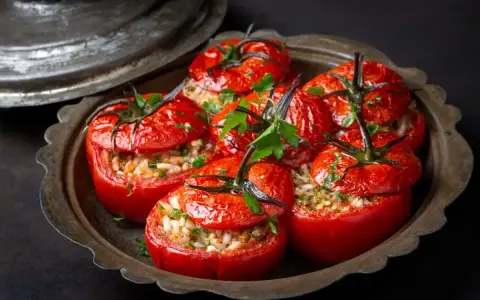 Tomates farcies au riz au four, garnies de persil frais, servies dans un plat en métal patiné. Un délice simple et savoureux.