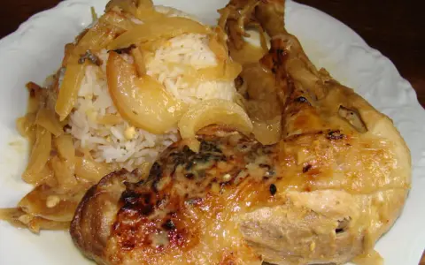 Un plat de poulet yassa savoureux avec du riz blanc et des oignons caramélisés.