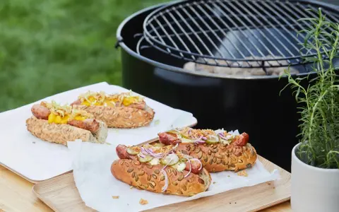 Délicieux hot dogs prêts pour un barbecue, avec des garnitures fraîches et un pain aux graines.