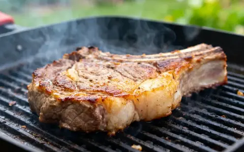 Un gros morceau de bœuf sur un gril, fumant doucement. La cuisson lente au barbecue révèle une croûte dorée et une chair juteuse.