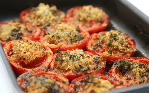 Tomates farcies au barbecue, gratinées et parsemées d'herbes fraîches, prêtes à être dégustées.