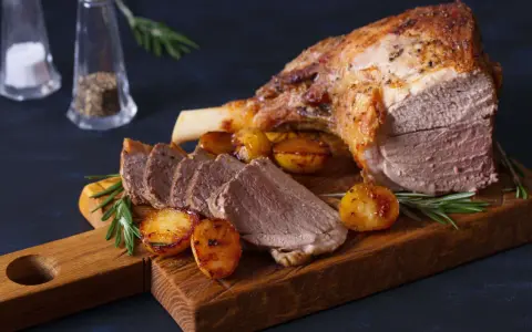 Gigot d'agneau rôti, pommes de terre et romarin sur une planche en bois. Un plat parfait pour la viande pour Pâques.