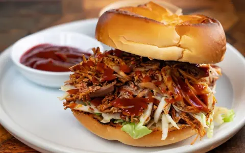 Burger généreux garni d'effiloché de porc savoureux, de salade croquante et nappé de sauce barbecue. Un délice !