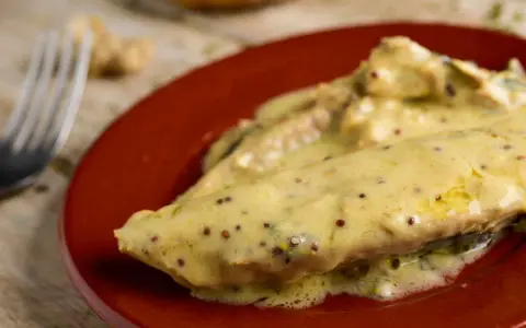 Poisson nappé d'une onctueuse sauce moutarde, servi sur une assiette rouge. Un délice !