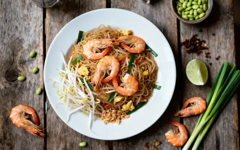 Délicieux Pad Thaï aux crevettes, une recette simple et savoureuse. Nouilles, pousses de soja, œuf, oignons verts et crevettes.