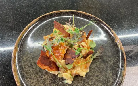 Une assiette de truffade recette, garnie de fines herbes et de lardons croustillants. Un plat réconfortant et savoureux.