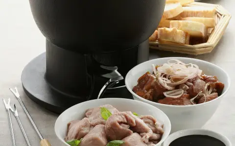 Préparation d'une fondue bourguignonne : viande blanche crue, viande cuite, pain et sauce. Des fourchettes à fondue sont prêtes.