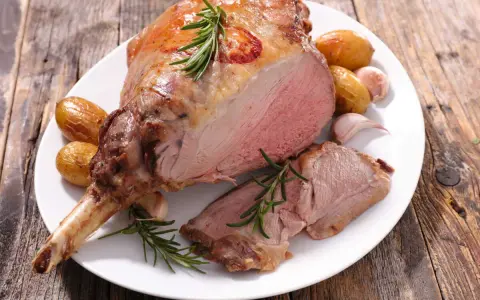 Gigot d'agneau rôti, tendre et juteux, accompagné de pommes de terre et d'ail. Un plat parfait pour un gigot pour 10 personnes.