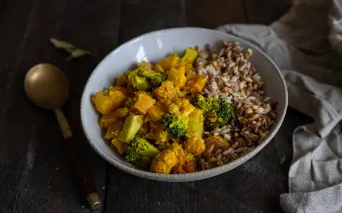 Un bol de riz et un curry de légumes coloré avec du brocoli, de la courge et des pois chiches.