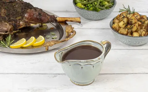 Sauce onctueuse pour accompagner une tranche de gigot d'agneau, avec des pommes de terre rôties et des légumes verts.