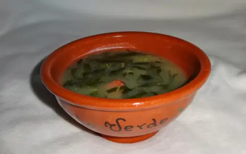 Un bol en terre cuite orné du mot "Verde" contient un délicieux caldo verde, une soupe portugaise réconfortante aux légumes verts.