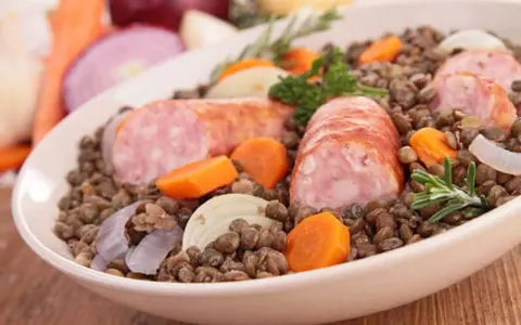 Un plat réconfortant de saucisses lentilles, garni de carottes, oignons et romarin.
