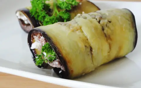 Rouleaux d'aubergine farcie au fromage et aux herbes, garniture appétissante.