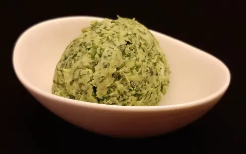 Une boule de beurre à l'ail et au persil dans un bol blanc. Parfait pour accompagner vos plats !