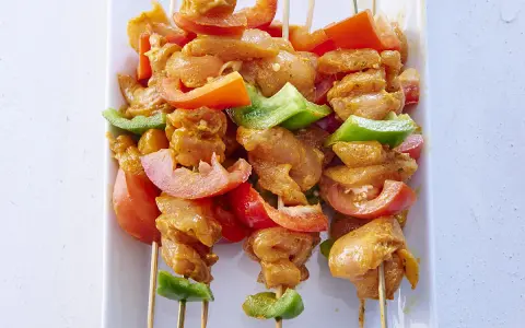 Brochettes de poulet marinées, tomates et poivrons verts, prêtes pour une recette brochette poulet barbecue.