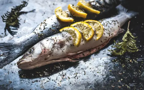 Deux poissons entiers, assaisonnés d'herbes et garnis de rondelles de citron, prêts pour un quel poisson barbecue.