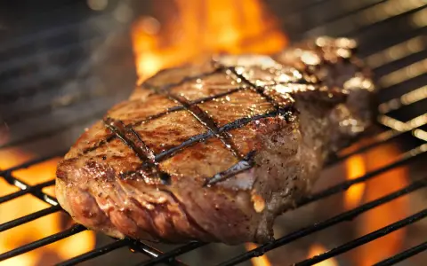 Un délicieux faux filet barbecue, marqué par les flammes, cuit à la perfection sur un grill.