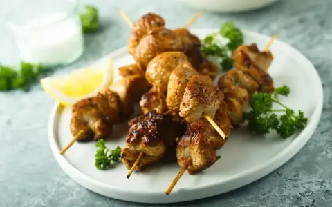 Brochettes de poulet citronnées, dorées et juteuses, garnies de persil frais et d'un quartier de citron. Un délice à savourer !