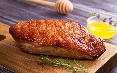 Un magret de canard au barbecue, la peau dorée et croustillante, servi sur une planche en bois avec du thym frais et une sauce au miel.