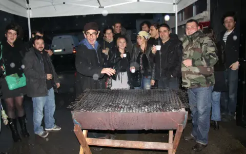 Un groupe d'amis profite d'un barbecue sous la pluie, sous un abri. L'ambiance est conviviale malgré les gouttes.