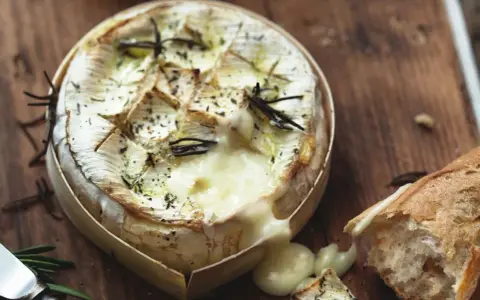 Camembert fondant au barbecue gaz, arrosé d'herbes et servi avec une baguette croustillante. Un délice à partager.