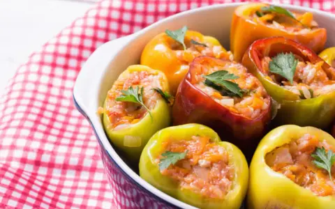 Poivrons colorés farcis de riz et de légumes, garnis de persil frais. Un plat savoureux de légumes farcis.