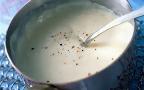 Sauce béchamel sans beurre, onctueuse et parsemée de poivre, prête à être dégustée.