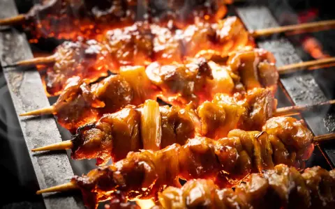 Brochettes de bœuf et fromage grillées sur des braises ardentes, dégageant une fumée alléchante.