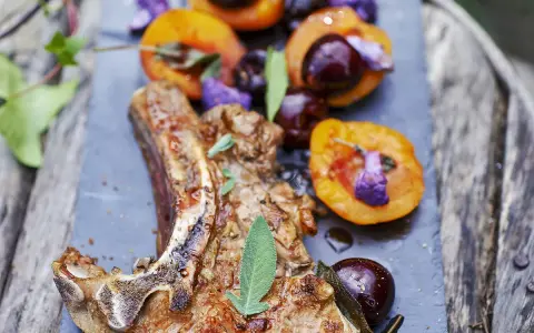 Délicieuse côte de veau barbecue, servie avec des abricots rôtis et des cerises, garnie de sauge fraîche.